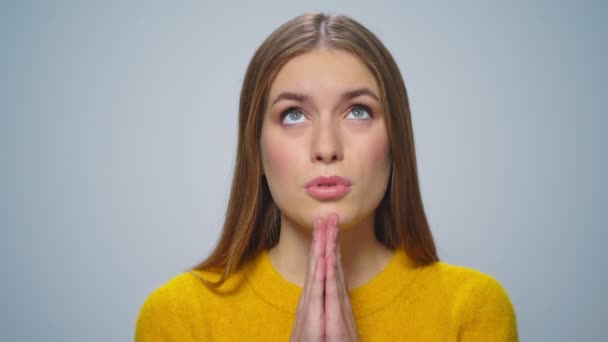 Портрет привлекательной молодой женщины, молящейся перед камерой на сером фоне. — стоковое видео