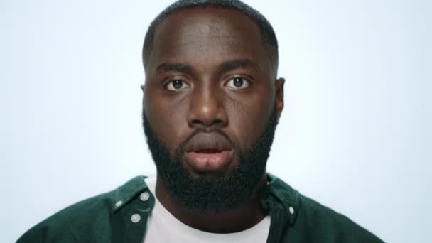 Porträt eines positiven Afrikaners, der vor grauem Hintergrund lustige Gesichter macht. — Stockvideo
