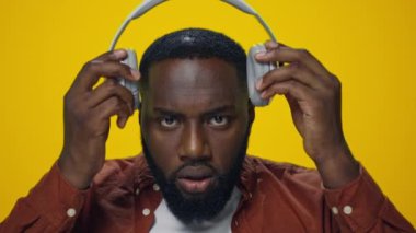 Stüdyoda kulaklıkla müzik dinleyen şaşırmış Afrikalı adamın portresi..
