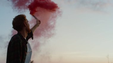 Sis bombası tutan adam. Mutlu adam dağın zirvesinde zaferi kutluyor.