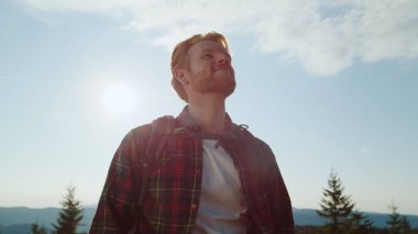 Yürüyüşçü dağlarda yürüyüş yaparken dinleniyor. Yeşil araziye bakan bir adam.