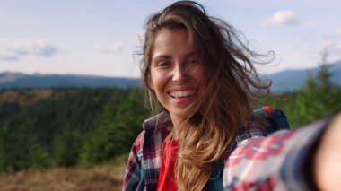 Dağlarda görüntülü sohbet eden mutlu bir kız. Kameraya el sallayan kadın