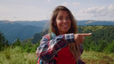 Dağlarda kameraya bakan gülümseyen kadın. Sırt çantası takan kadın turist