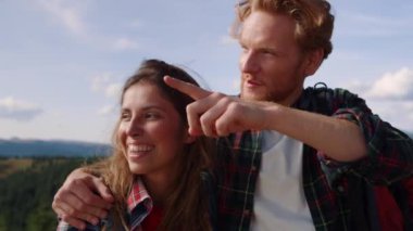 Dağlarda manzaraya bakan turistler. Kız ve erkek işaret ediyor.