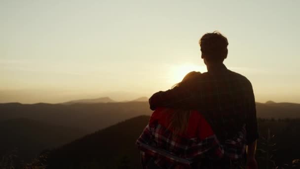 Пара дивиться на сонце, що стоїть за горою. Люблячий чоловік і жінка насолоджується заходом сонця — стокове відео