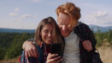 Kadın ve erkek akıllı telefondan iyi haberler okuyor. Yürüyüşçüler cep telefonu kullanıyor