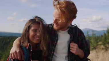 Dağın tepesinde cep telefonu olan mutlu çift.