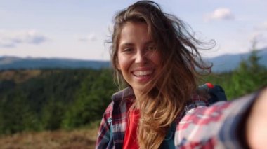 Dağlarda görüntülü sohbet eden mutlu bir kız. Kameraya el sallayan kadın