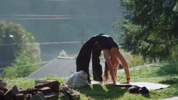 Aantrekkelijk meisje die bridge poseert op Hill. Yoga vrouw training buiten. — Stockvideo