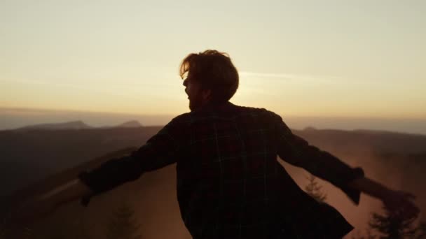 Мужчина танцует в горах на закате. Счастливчик жестикулирует руками во время танцев — стоковое видео