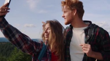 Dağlarda yürüyüş yaparken cep telefonuyla sohbet eden mutlu kadın ve erkek.