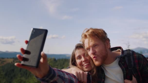 Cep telefonundan selfie çeken bir çift. Arkadaşlar kamerada mutlu yüzler çiziyor. — Stok video