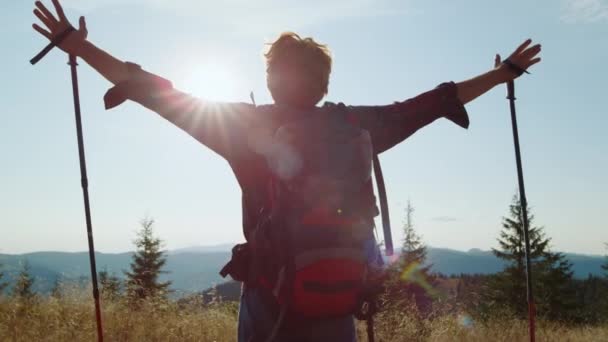 Dağın tepesinde duran adam. Erkek turist yürüyüş sırasında el kaldırıyor. — Stok video