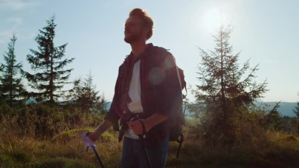 Hombre alegre con mochila trekking en las montañas. Sonriente hipster caminando por la carretera — Vídeos de Stock