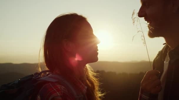 Speels meisje aanraken man gezicht met gras mes bij zonsondergang in de bergen — Stockvideo