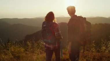Turistler dağlarda günbatımının tadını çıkarıyorlar. Çiftler birlikte vakit geçiriyorlar.