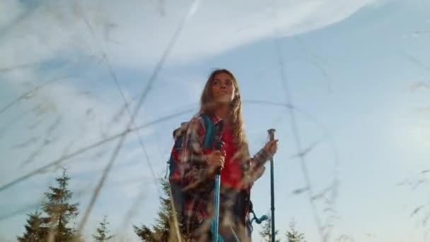 Uśmiechnięta kobieta spacerująca po trawiastym polu. Młoda kobieta wędrująca w górach — Wideo stockowe