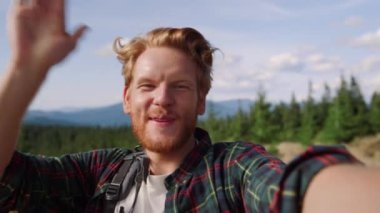 İnternette arkadaşınla görüntülü konuşma yapan adam. Erkek yürüyüşçü kameraya el sallıyor 