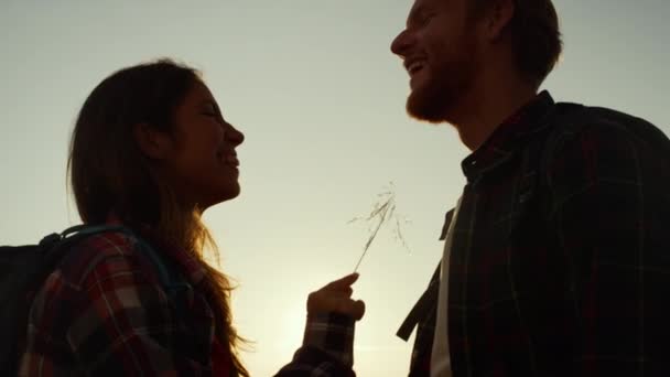 山の中で夕日を眺めながらバックパックを見て笑っているカップル — ストック動画