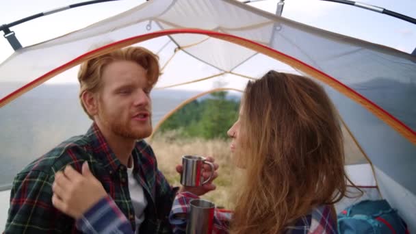 Meisje zorgt voor mannenhaar in campingtent. Koppel thee drinken uit mokken — Stockvideo