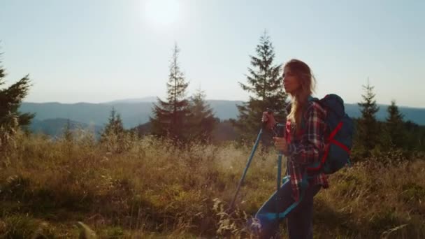 Senderismo turístico femenino en las montañas. Mujer con bastones de trekking caminando por la carretera — Vídeos de Stock