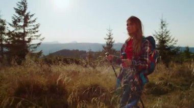 Ciddi bir kız tatilde dağlarda yürüyüş yapıyor. Dişi sırt çantalı gezgin yolda yürüyor