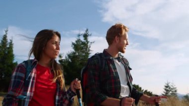 Tatilde bir çift dağ yürüyüşü. Erkek ve kadın yürüyüş sırasında konuşuyor.