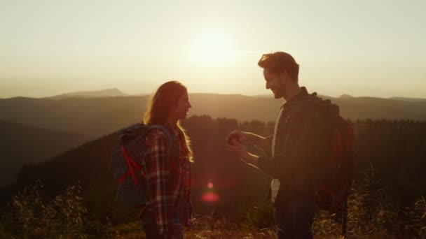 Туристи насолоджуються пішохідним туризмом у горах на заході сонця. Чоловік пропонує шлюб жінці — стокове відео