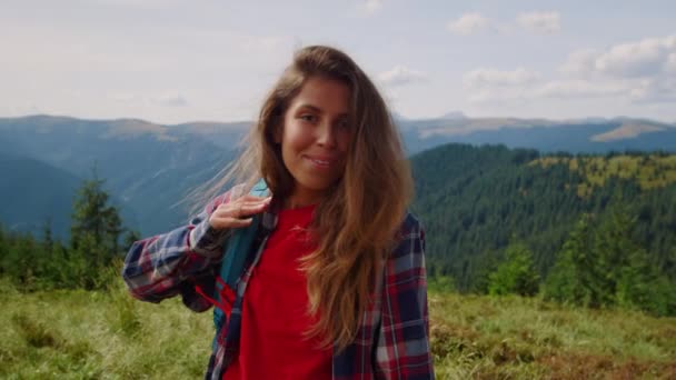 Uma mulher a usar mochila nas montanhas. Positivo hipster acenando a mão na câmera — Vídeo de Stock