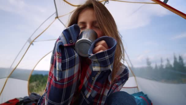 女性ハイカーはテントの中でマグカップからお茶を飲む。女の子と男座っている観光テント — ストック動画