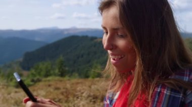 Dağlarda akıllı telefon kullanan bir kız. Cep telefonunda mesaj yazan kadın 