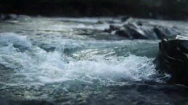 Dağ nehri suyunun yüzeyi su sıçrıyor. Doğada akan bol akarsu..