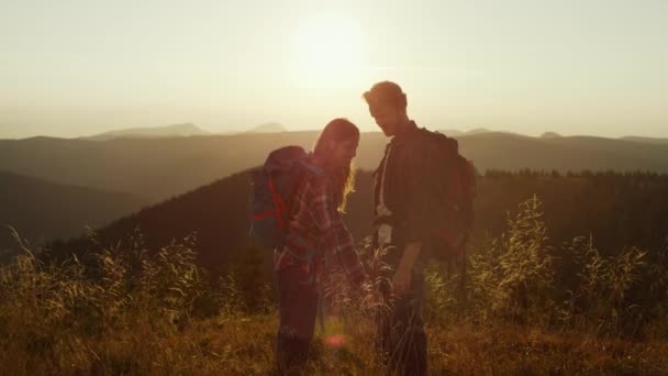 Paar staan op de top van de berg bij zonsondergang. Meisje flirten met jongen — Stockvideo