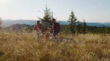 Gülümseyen adam ve kız sahada yürüyüş yapıyorlar. Turistler dağlarda yürüyor