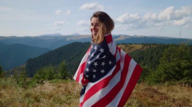 Ulusal Amerikan bayrağına sarılmış bir kadın. Yürüyüş sırasında kameraya poz veren kız