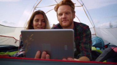 Genç çift, yürüyüş çadırındaki tablet bilgisayardan online video görüşmesi sırasında konuşuyor.