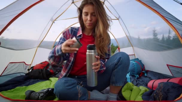 Attractive woman sitting in tent. Focused girl opening thermos with tea — Stock Video