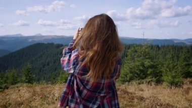 Genç bir kadın cep telefonuyla doğal manzaranın panoramik fotoğrafını çekiyor.