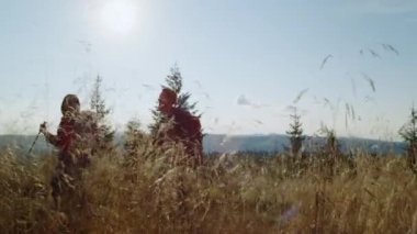 Kız ve erkek dağlarda yürüyüş yapıyor. Tarlada yürüyüş yapan pozitif bir çift.