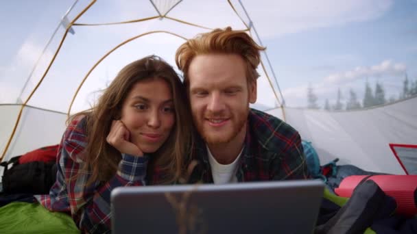 Женщина и мужчина используют цифровой планшет в палатке для кемпинга. Девушка и парень смотрят фильм — стоковое видео