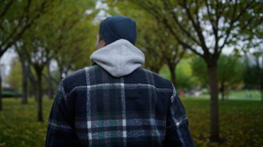 Sonbahar parkında yürüyen genç adamın arka görüntüsü. Kafkasyalı adama yaklaş..