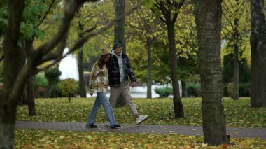 Geniş açıda mutlu genç bir çift yol boyunca el ele yürüyor..