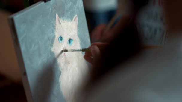 Oigenkännlig flicka konstnär rita bild av vit katt på duk i studio. — Stockvideo