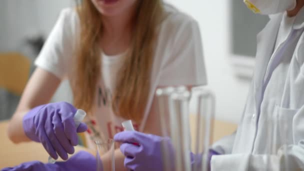 Άτομα που σπουδάζουν χημεία με γάντια προστασίας και μάσκα στη σχολική τάξη. — Αρχείο Βίντεο
