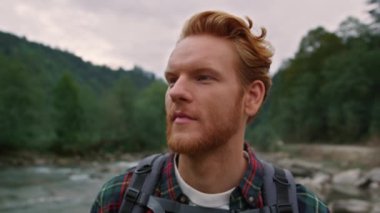 Dağ manzarasına bakan mutlu bir adam. Nehir kıyısında turist yürüyüşü