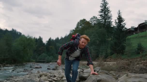Muž kráčející po skalách u řeky. Muž turista objevující přírodu v horách — Stock video