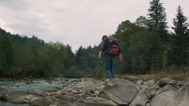 Άνθρωπος που περπατάει σε βράχους στο ποτάμι. Άρρεν τουριστική πεζοπορία κατά μήκος του ποταμού στο δάσος — Αρχείο Βίντεο