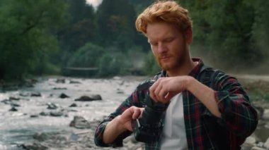 Nehir kıyısında duran bir turist. Fotoğrafçı kamera lensinden kapağı kaldırıyor 