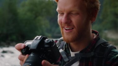 Kamerayı elinde tutan bir yürüyüşçü. Fotoğrafçı kamerada resimlere bakıyor