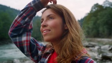 Dağlarda nehirde duran bir kadın. Kameraya bakan gülümseyen kızın portresi